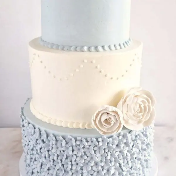 A three layer cake with blue frosting and white icing.