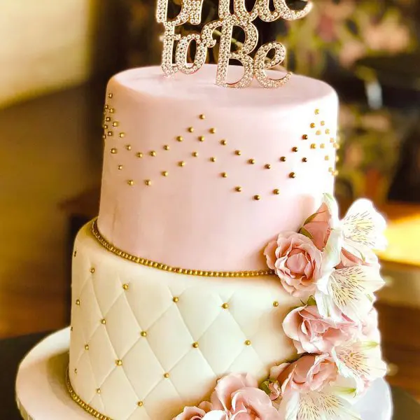 A pink and white cake with flowers on top of it.