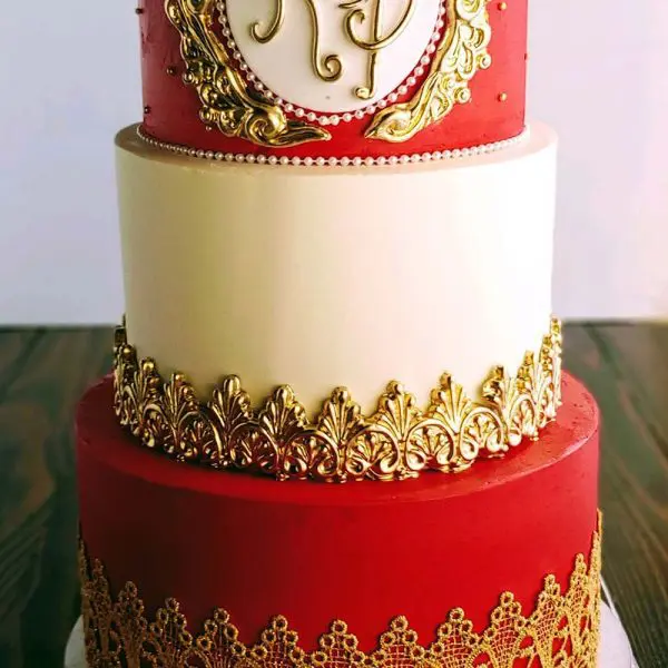 A red and white cake with gold trim