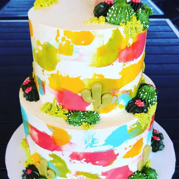 A two layer cake with colorful frosting and fruit.