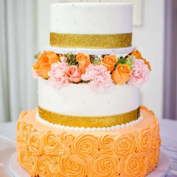 A three layer cake with orange and white frosting.