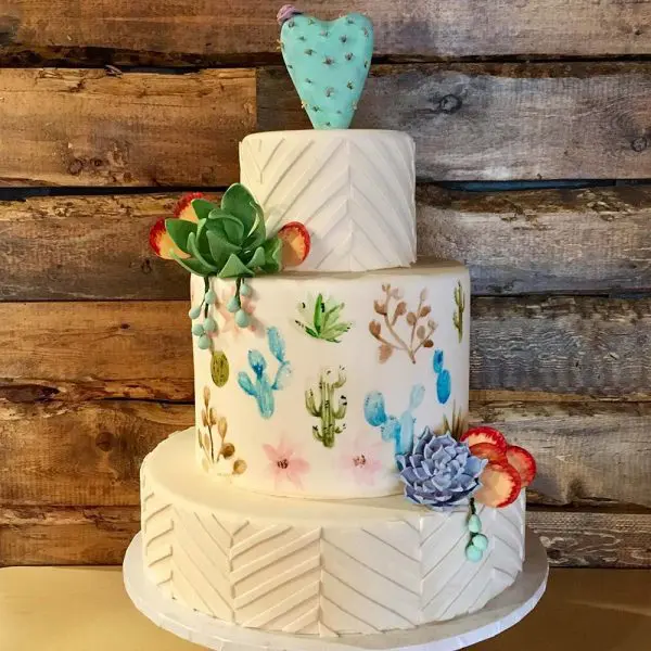 A three tiered cake with cactus and succulents on it.