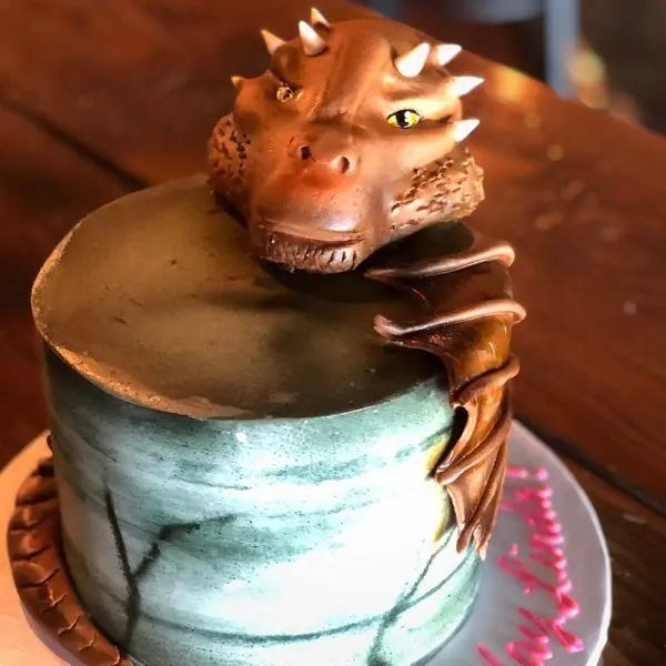 A cake with a dragon head on top of it.