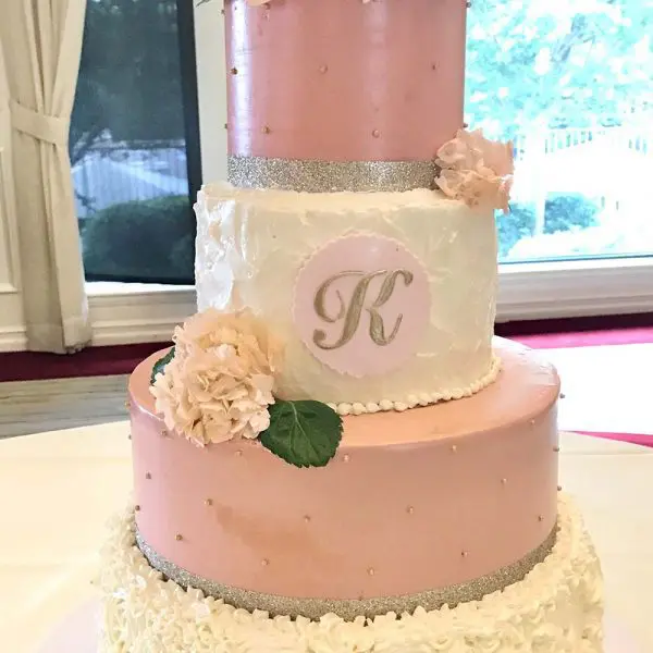 A pink and white cake with flowers on top of it.