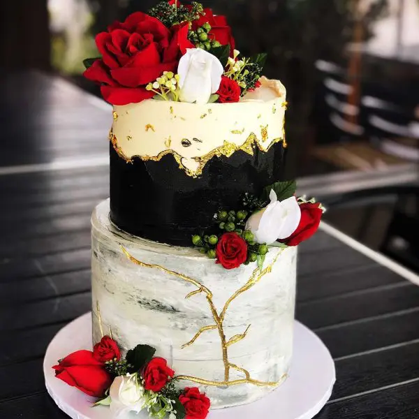 A two layer cake with red roses on top of it.