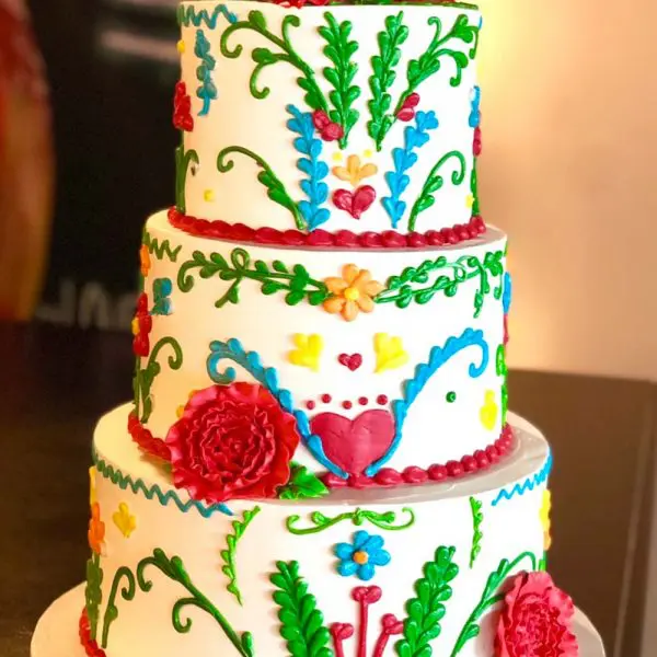 A three tiered cake with colorful designs on it.