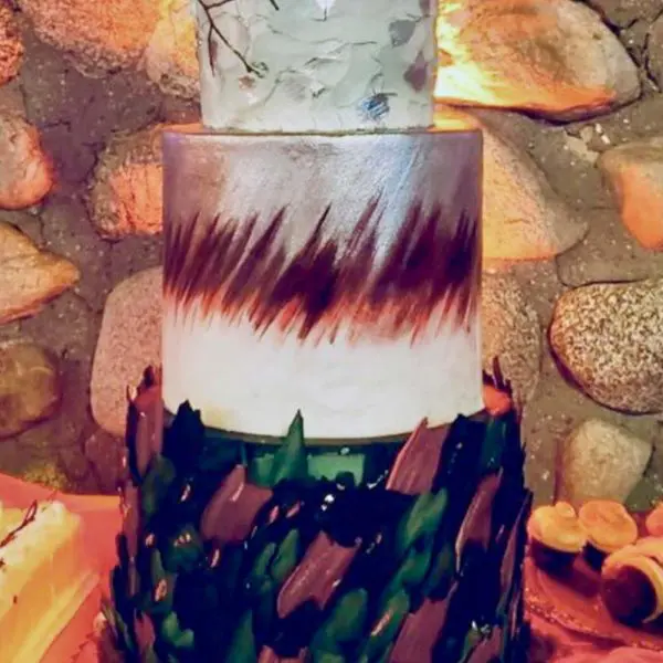 A three layer cake with leaves and a candle on top.