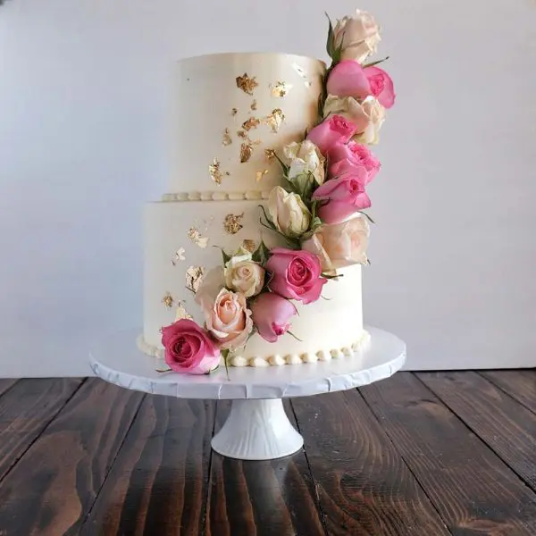 A two layer cake with pink flowers on top of it.