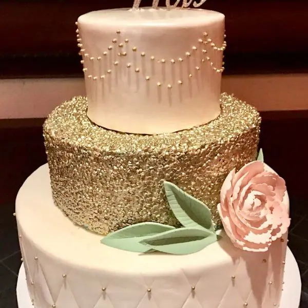 A three tiered cake with gold and white frosting.