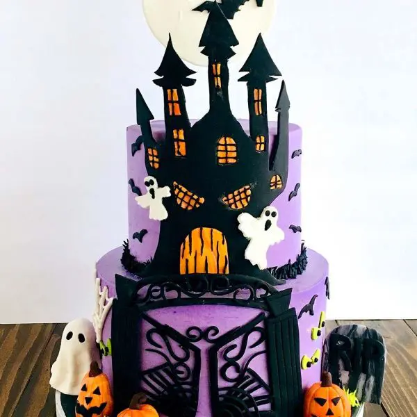 A purple cake with bats, ghosts and a castle.