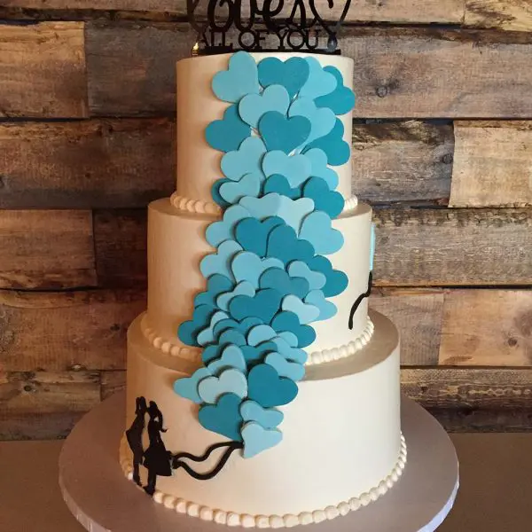 A three tiered cake with blue hearts on the side.