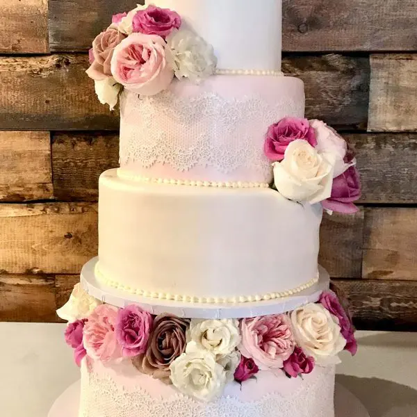 A four layer cake with pink flowers on it.