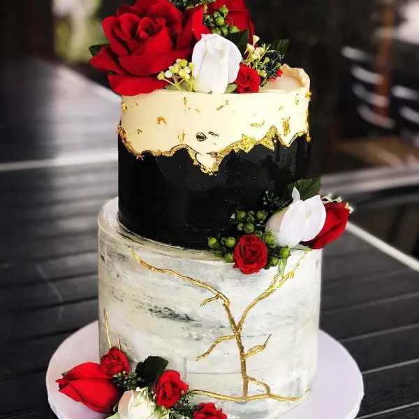 A two layer cake with red roses on top of it.