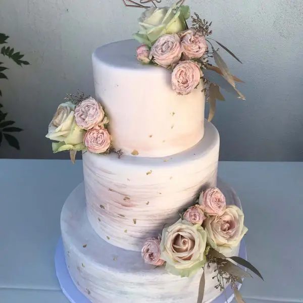 A three layer cake with pink flowers on top.