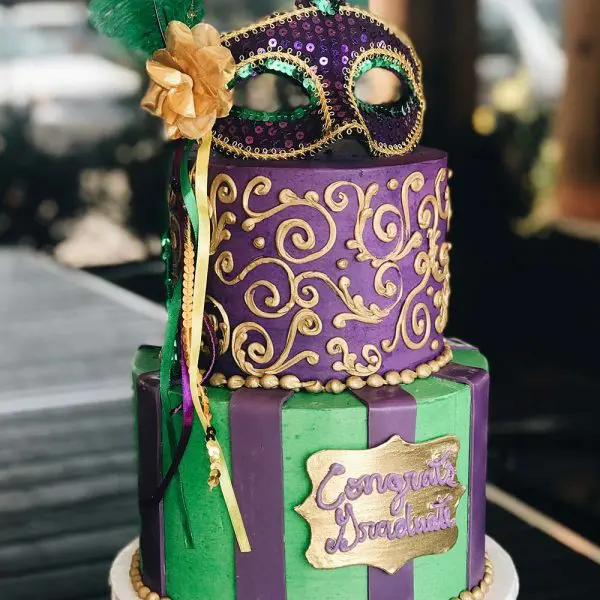 A purple and green cake with a mask on top.