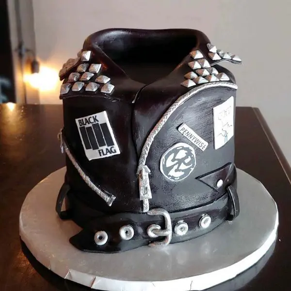 A cake with black leather jacket and silver studs.