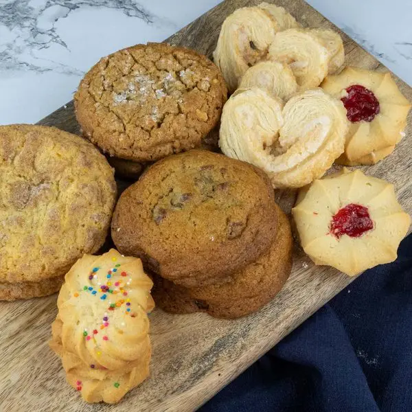 A wooden cutting board topped with lots of cookies.