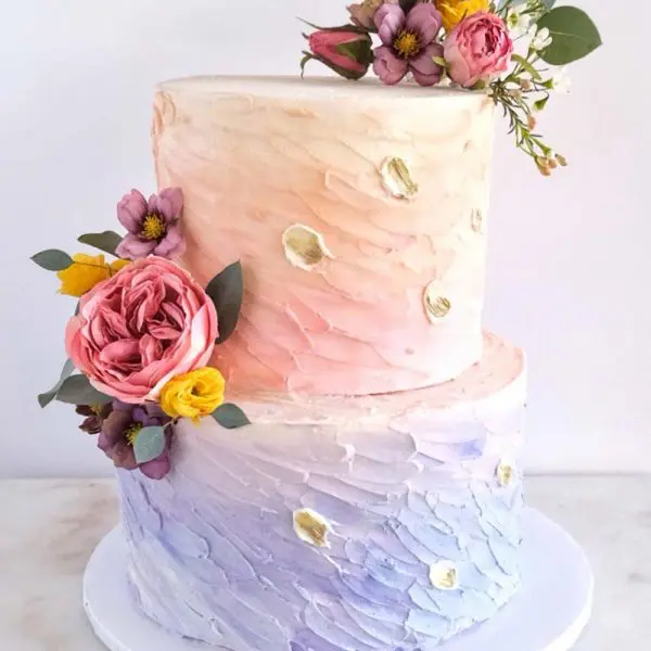 A two layer cake with flowers on top of it.