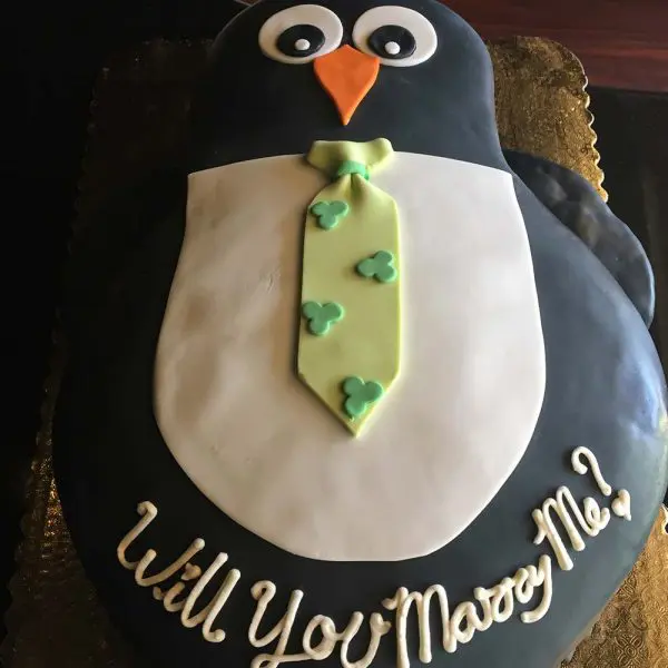 A penguin cake with a tie on top of it.