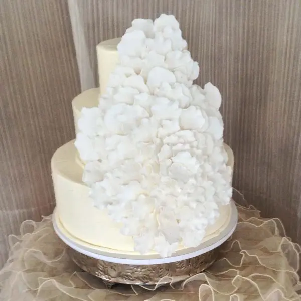 A white wedding cake with a large amount of sugar on top.