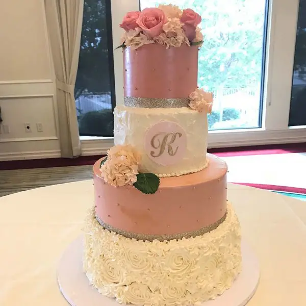 A pink and white cake with flowers on top of it