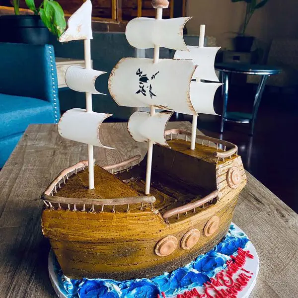 A cake shaped like a pirate ship on top of a table.