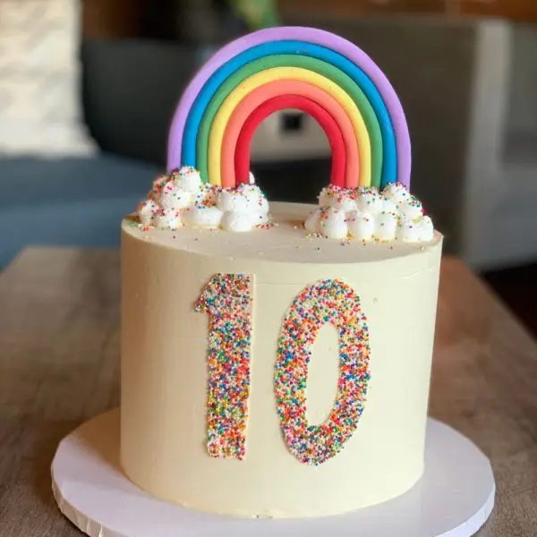 A birthday cake with sprinkles and rainbow on top.