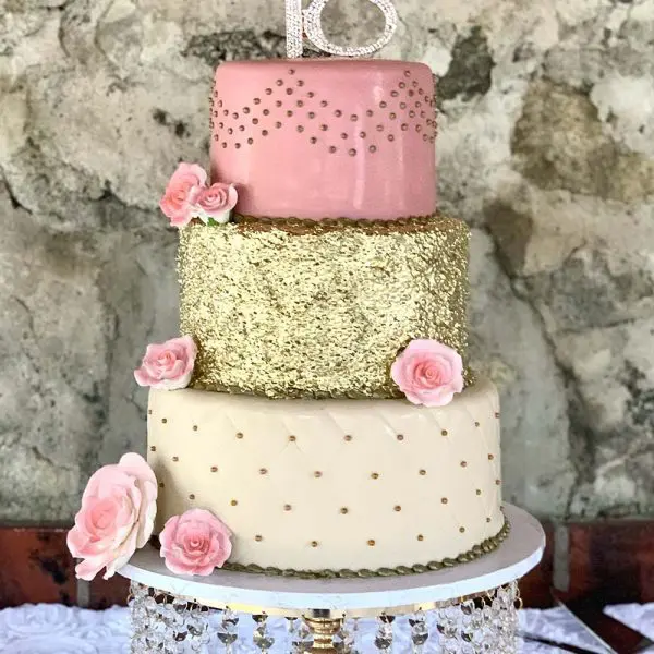 A three layer cake with pink and gold decorations.