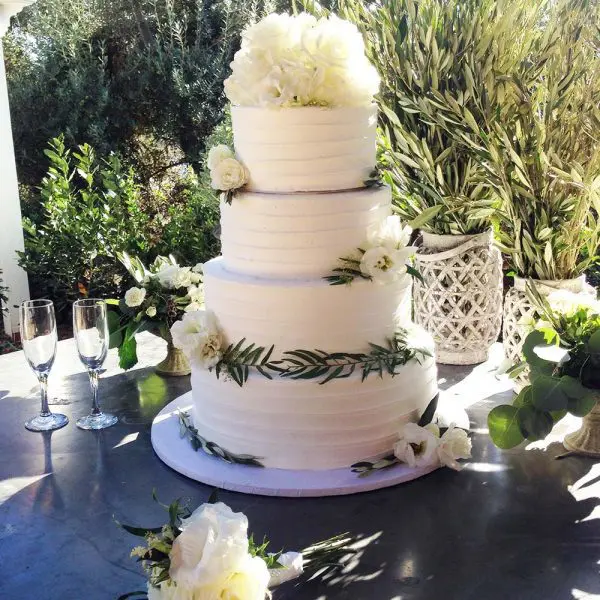 A white wedding cake with flowers on top of it.