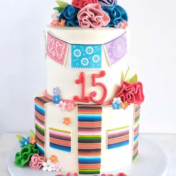 A birthday cake with colorful stripes and flowers.