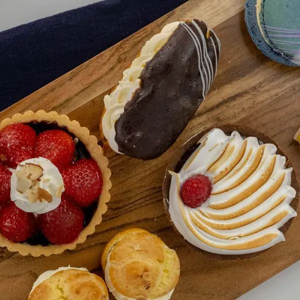 A wooden tray topped with pastries and strawberries.