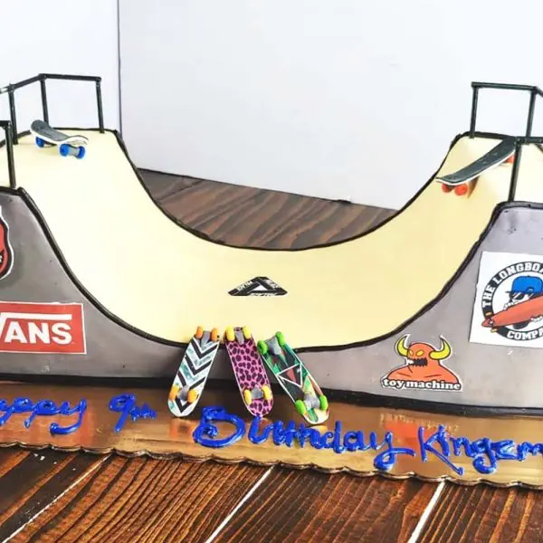 A skateboard ramp cake is shown on the floor.