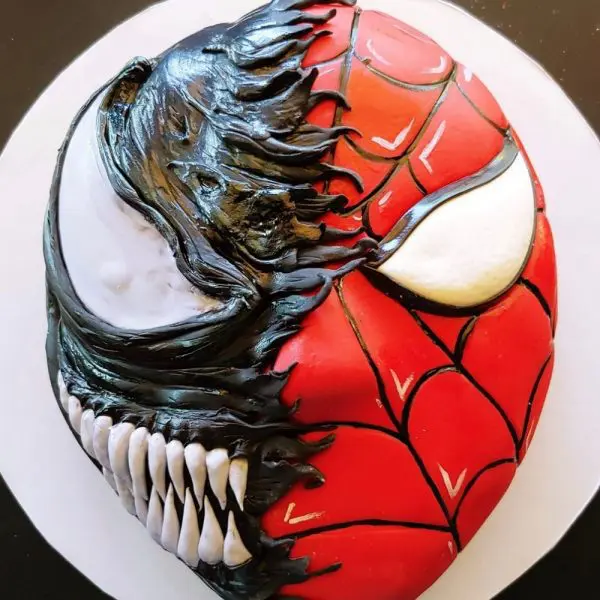 A cake with a venom and spider man face on it.