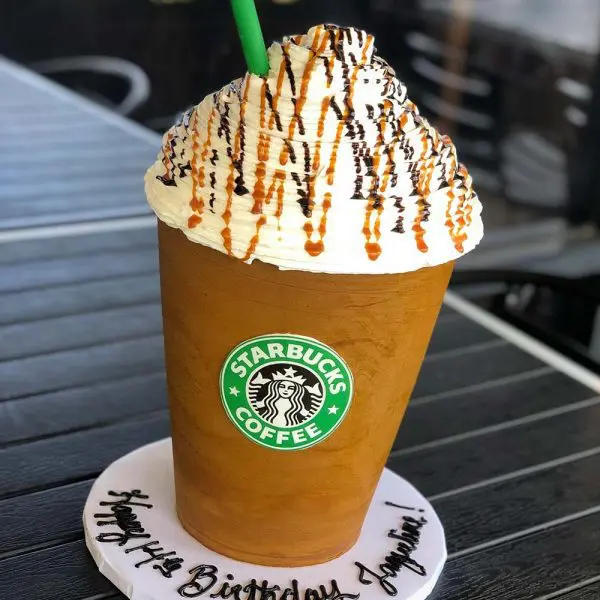 A starbucks coffee cup cake with whipped cream and chocolate.