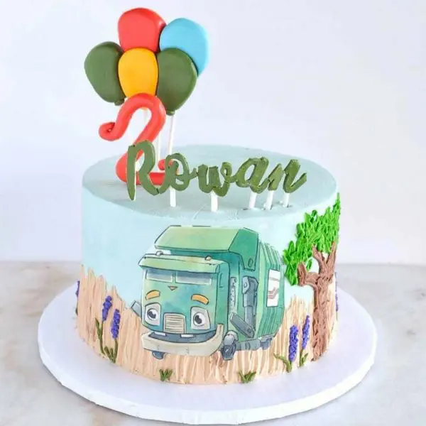 A cake with balloons and a truck on top of it.