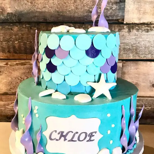 A two layer cake with blue and purple decorations.