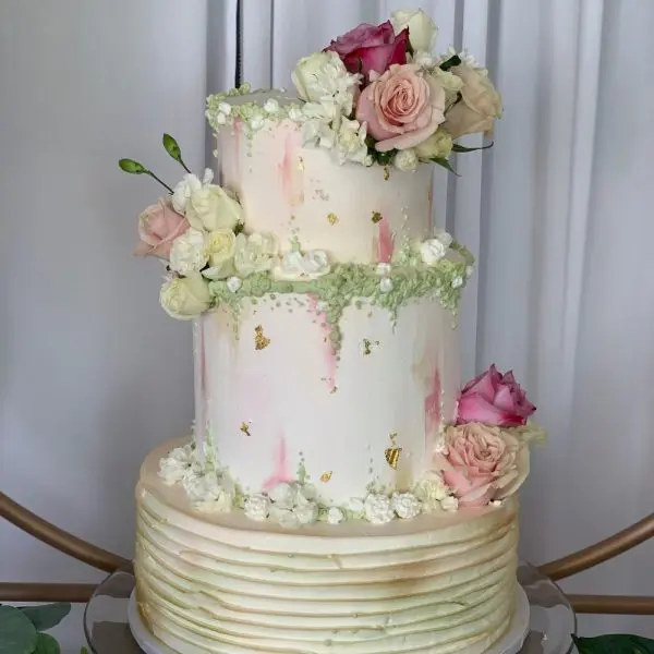 A two tiered cake with pink flowers on top.