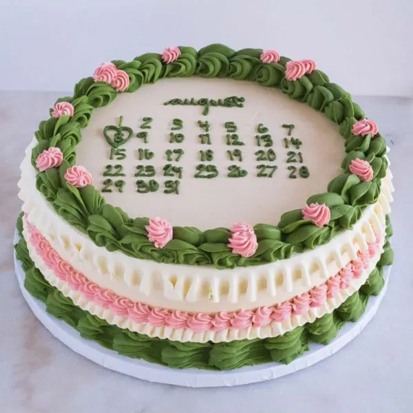 A cake with green and pink frosting on top of it.