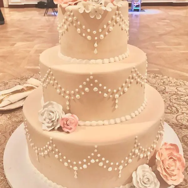 A three layer cake with pink flowers on top of it.