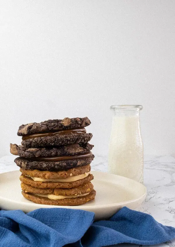 Stack of assorted cookies with a glass of milk.